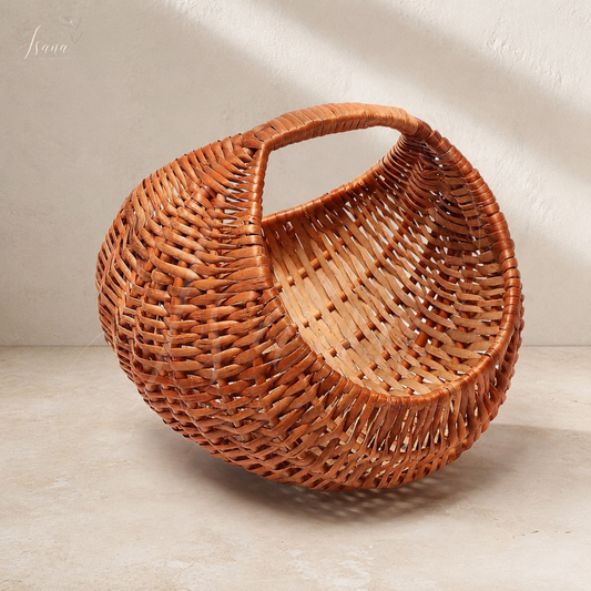 A round woven rattan basket with a single integrated handle, shown on a textured beige floor against a neutral wall with soft diagonal shadows.